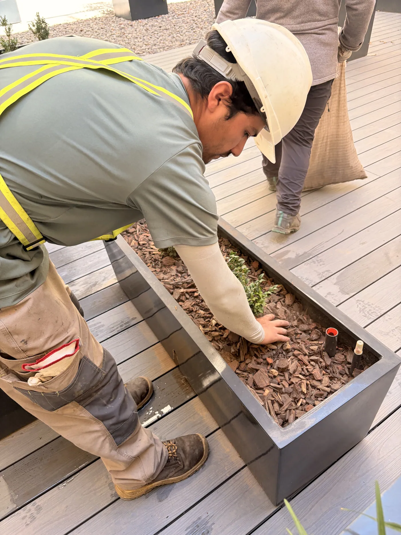 Trabajador reponiendo mulch en jardinera de patio interior